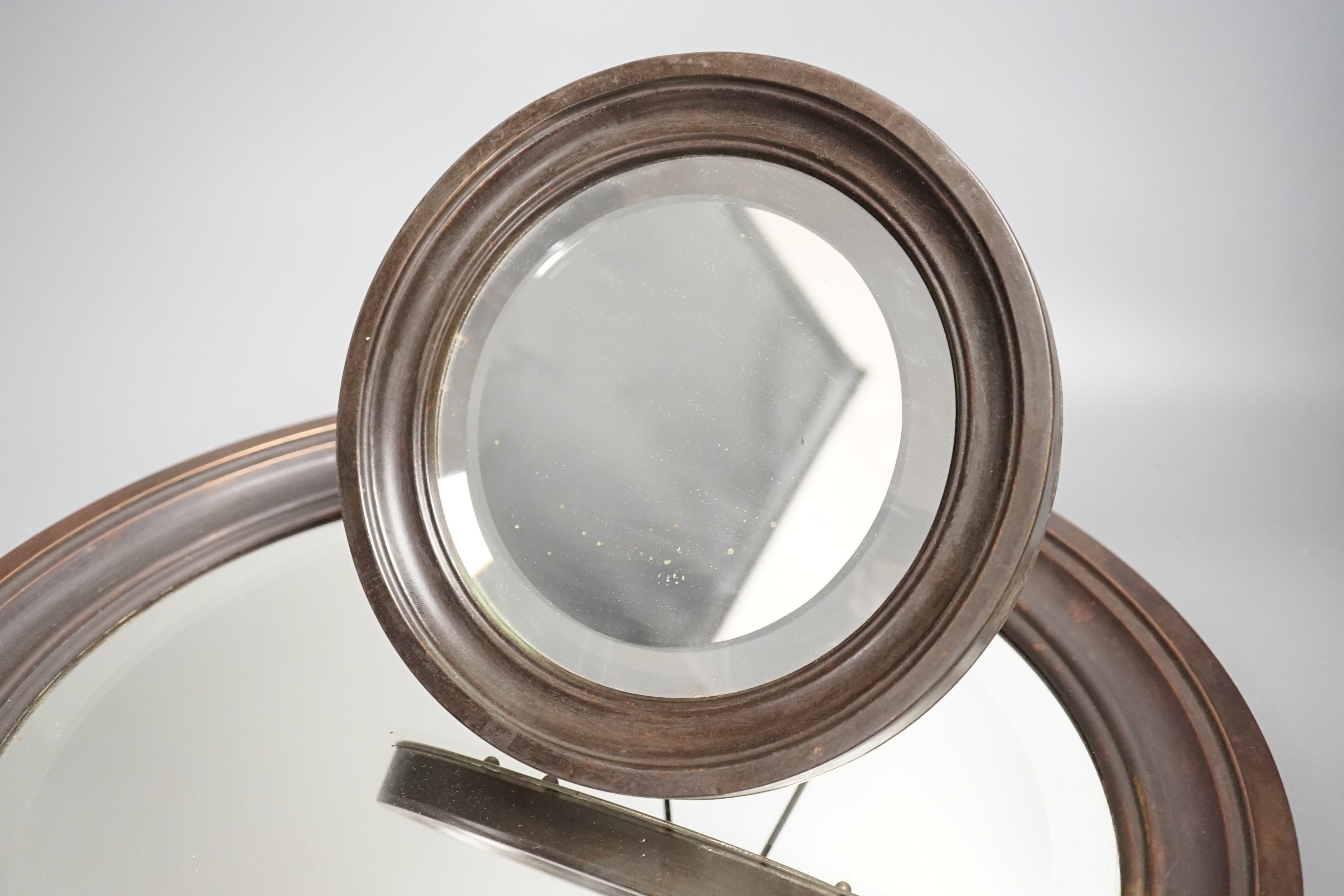 A brass framed circular mirror ‘ALBANY MIRROR BRITISH MADE PAT No 10405 203041-236189’ to reverse and a copper framed mirror, largest 43 cms diameter.